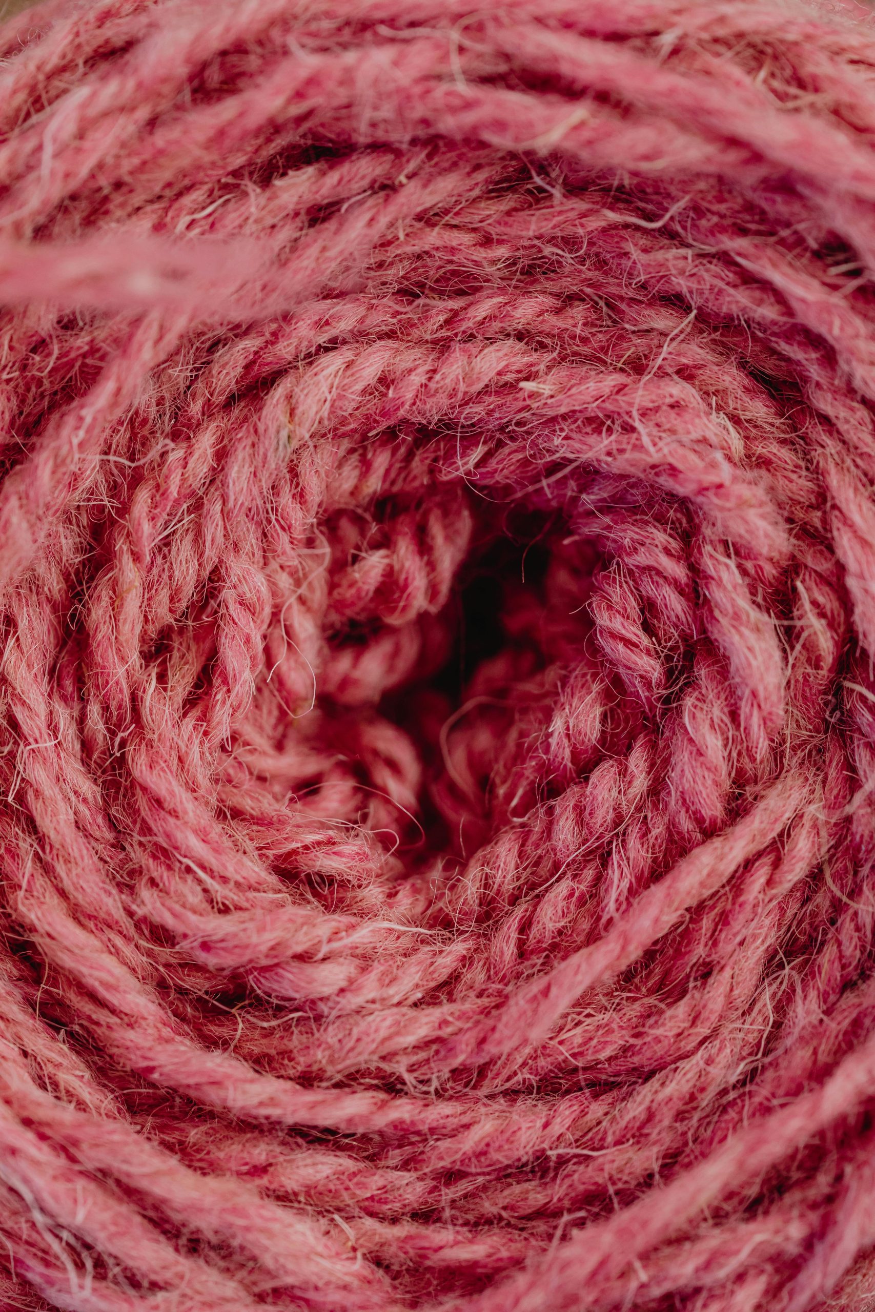 Detailed close-up of pink wool yarn spun into a spiral, showcasing texture.